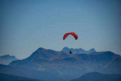 Low angle view of person paragliding against mountain