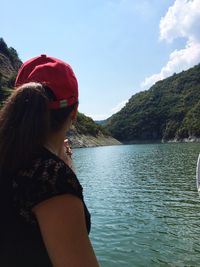 Side view of woman standing by water against sky