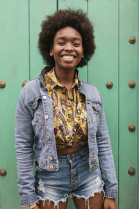 Curly hair woman smiling while standing in front of wall