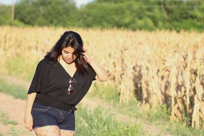 Woman with hand in hair walking on grassy field