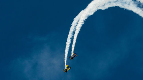 Low angle view of airplane flying against clear blue sky