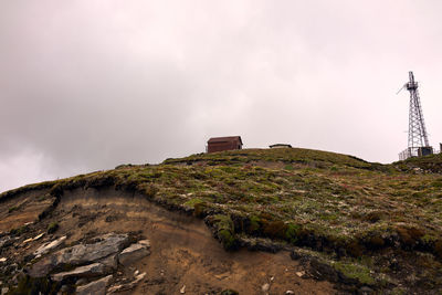 Low angle view of cabin on mountain against sky