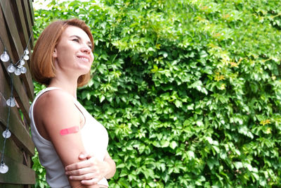 Smiling woman glasses with a plaster on her hand rejoices from receiving a vaccination against 