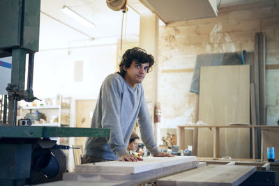 Thoughtful carpenter standing at workbench