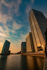 Modern buildings by city against sky during sunset