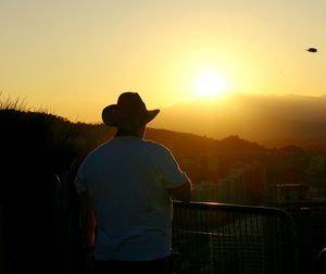 Rear view of people standing on landscape at sunset