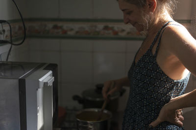 Caucasian woman in the kitchen cooking and looking at the pan. salvador, bahia, brazil.