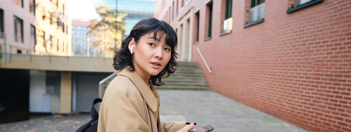 Young woman standing against building