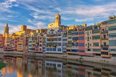 Buildings by river against sky in city