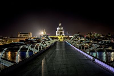 Illuminated footbridge over canal amidst buildings in city at night