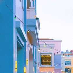 Low angle view of illuminated buildings against clear blue sky