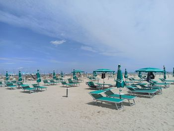 Chairs on beach against blue sky