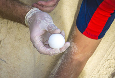 Close-up of hand holding ball on sand