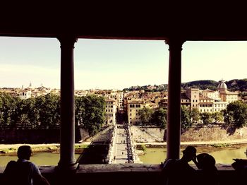 Rear view of man sitting in city against sky