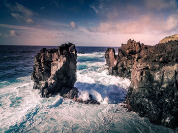 Scenic view of rocks on beach against sky