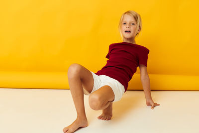 Full length portrait of young woman sitting on floor