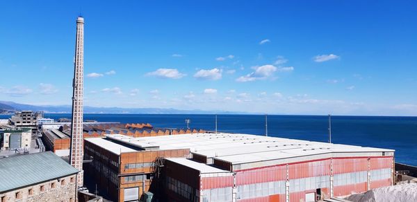 Buildings by sea against blue sky