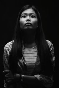 Beautiful young woman looking up against black background