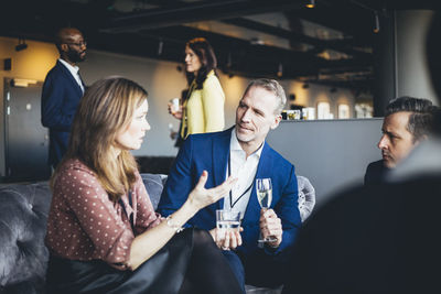 Female professional talking to male colleagues while sitting in office