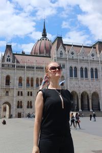 Woman standing by historic building against sky