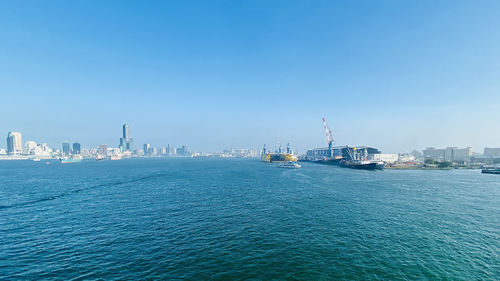 Boats in sea against clear blue sky