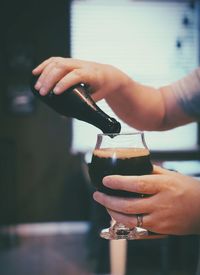 Close-up of hand pouring stout beer drink