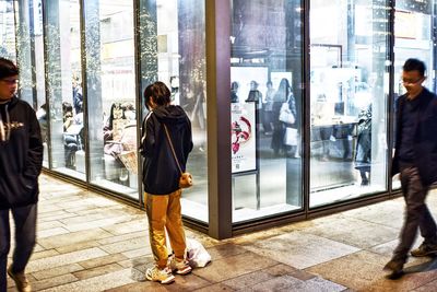 People standing by glass window in store