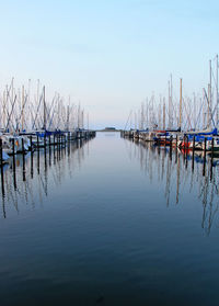 Boats moored in sea against clear blue sky