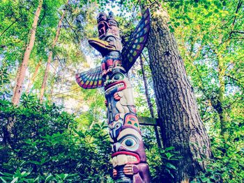 Low angle view of statue by trees in forest