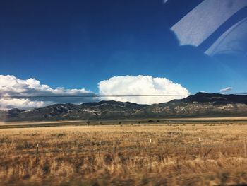 Scenic view of field and mountains against sky