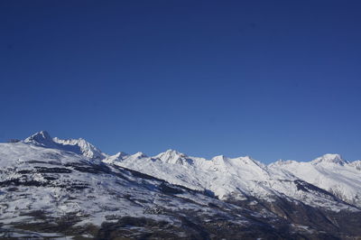 Scenic view of snowcapped mountains against clear blue sky