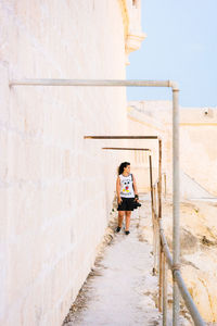 Young woman standing on steps against sky