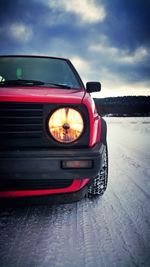 Reflection of car in lake against sky during winter