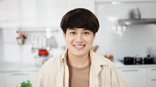 Portrait of handsome gay, attractive young gay smile in kitchen room.