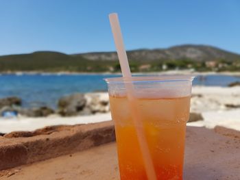 Close-up of drink on beach against sky