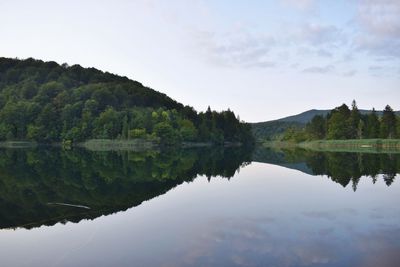 Scenic view of lake by trees against sky