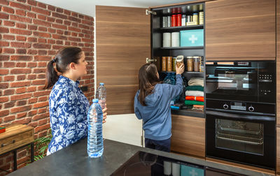 Side view of woman using mobile phone while standing against wall