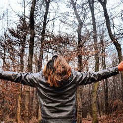 Rear view of woman with umbrella against trees