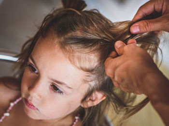 Cropped hands of mother braiding daughter hair