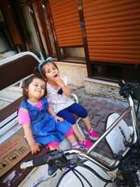 Full length of mother and girl sitting outdoors