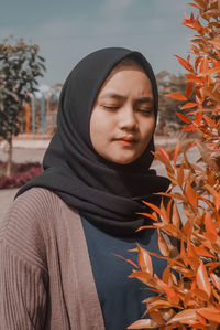 Portrait of beautiful young woman with autumn leaves