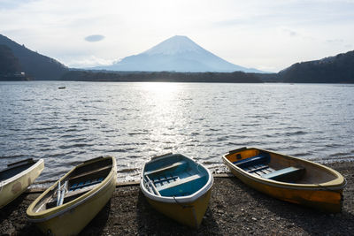 Boats moored on lake against mountains