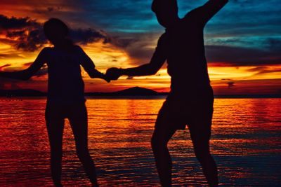 Silhouette woman standing on beach during sunset