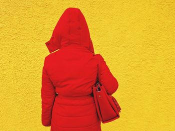 Rear view of woman standing against yellow wall