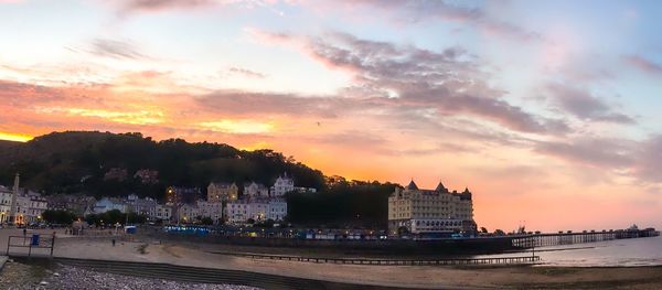 Buildings by sea against sky during sunset