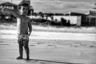 Full length of shirtless baby boy standing at beach against sky