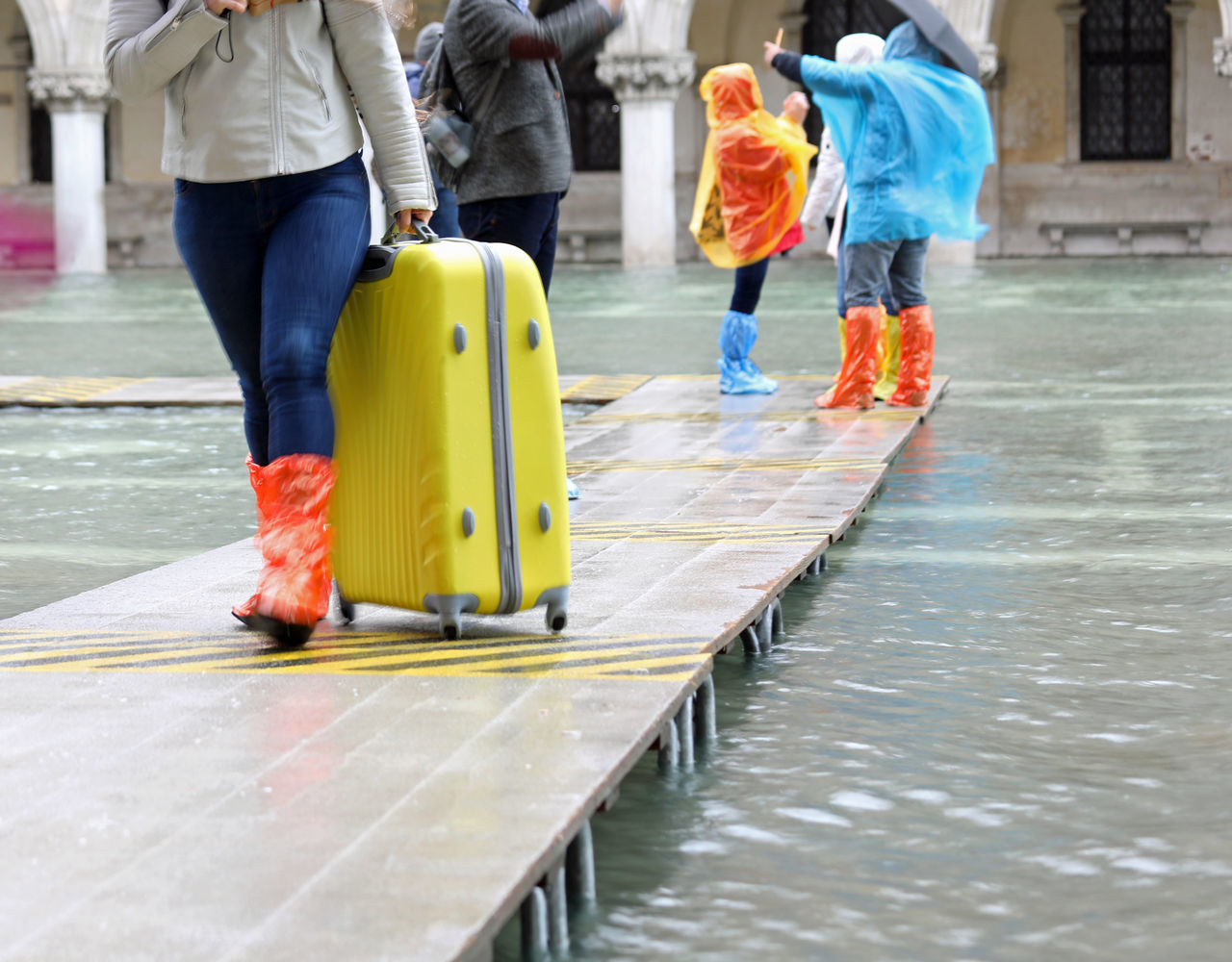 LOW SECTION OF PEOPLE WALKING ON ZEBRA CROSSING AT WATER