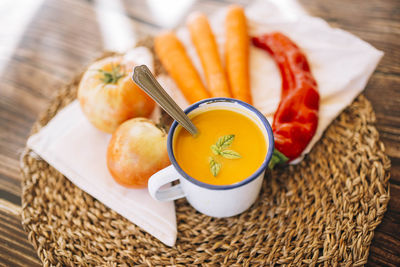 Top view of vegan pumpkin cream in an enameled mug with vegetables, peppers leek and tomatoes