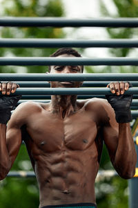 Rear view of shirtless man standing on railing