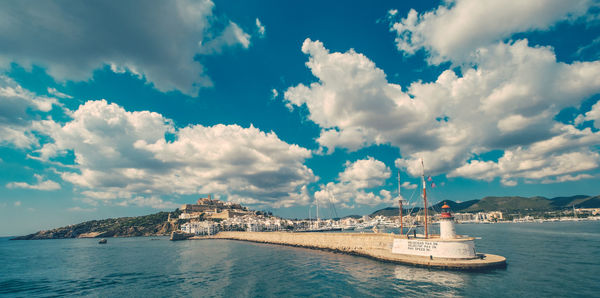 Boats in sea against cloudy sky